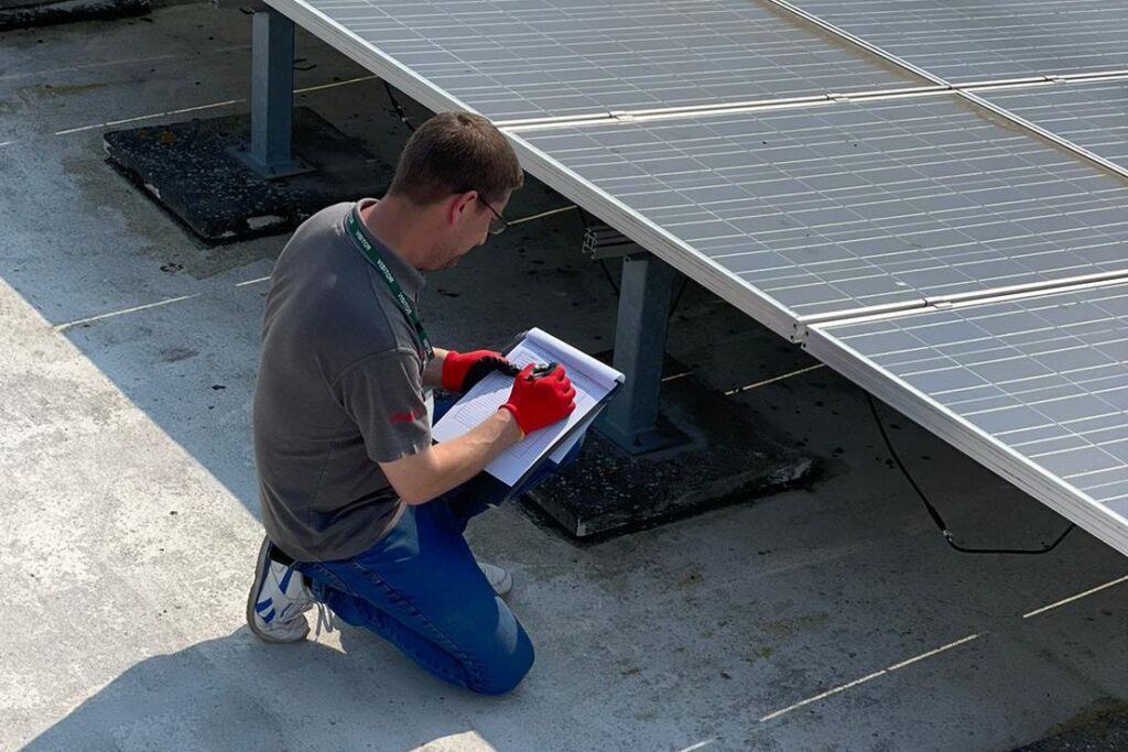 Elektra Smart Energy engineer inspecting solar panels and taking notes