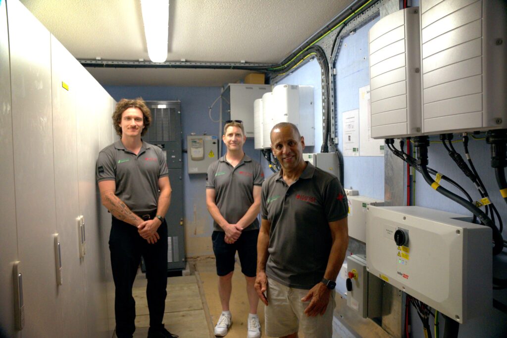 Elektra Smart Energy engineers posing beside intricate solar battery storage installation at commercial premises